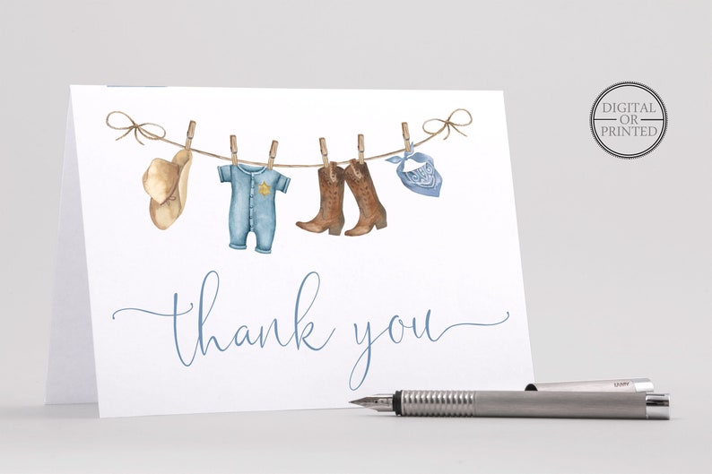 May include: A white thank you card with a blue baby onesie, brown cowboy boots, a cowboy hat, and a blue bandana hanging on a clothesline. The text "thank you" is written in blue cursive.