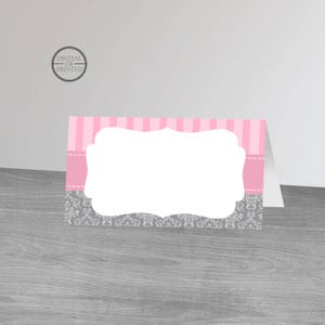 May include: Pink and gray place card with a decorative frame and a blank space for a name. The card has a pink and white striped pattern and a gray damask pattern.