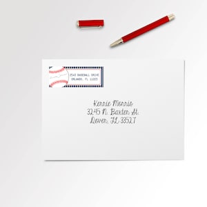 May include: A white envelope with a blue and red baseball-themed address label. The label has a baseball graphic and the text "2543 BASEBALL DRIVE ORLANDO, FL 11223". The envelope also has handwritten text: "Kerrie Morris 32.45 N. Baxter St. Dover, FL 33527"