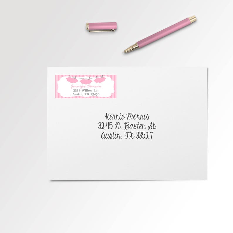 May include: A white envelope with a pink and white address label. The label has a pink and white striped background with a white border. The label has a pink banner with the text "Jennifer Drumeon" and the address "2314 Willow Ln. Austin, TX 23456". The envelope has a handwritten address in black ink: "Kennie Morris 32.45 N. Baxter St. Austin, TX 33527"
