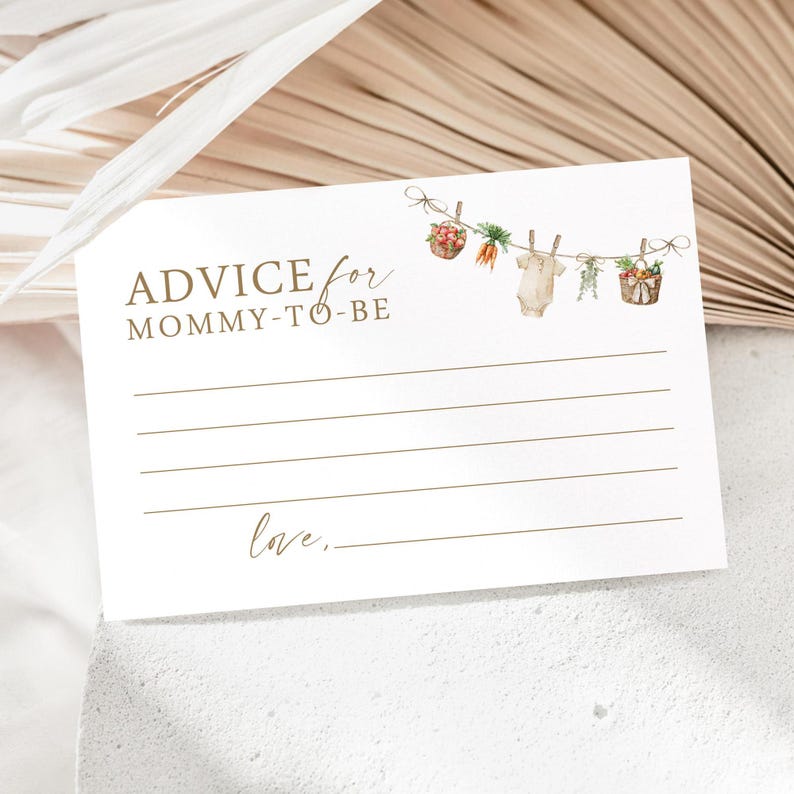 May include: A white card with brown text that reads "Advice for Mommy-to-Be". There are illustrations of a baby onesie, carrots, and baskets of fruit hanging from a string with clothespins.