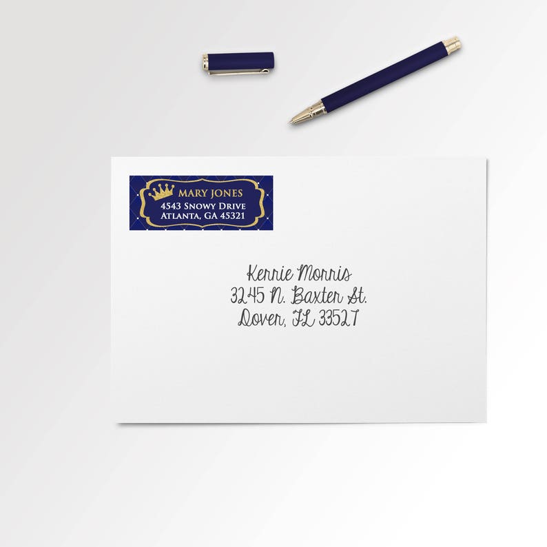 May include: A white envelope with a blue and gold address label featuring the name "MARY JONES" and address. A matching blue pen and pen cap are placed above the envelope. The envelope also has a handwritten address.