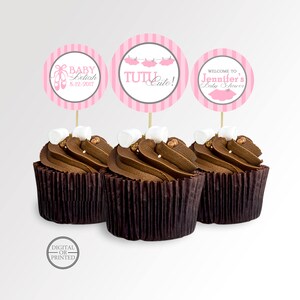 Puede incluir: Tres cupcakes de chocolate con adornos de cupcake rosa y gris. Los adornos tienen texto que dice "Baby Leilah 8-12-2017", "Tutu Cute!" y "Bienvenido al baby shower de Jennifer".