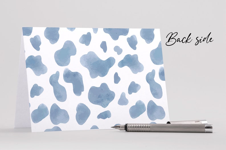 May include: A white card with a blue watercolour cow print pattern. The back side of the card is blank.