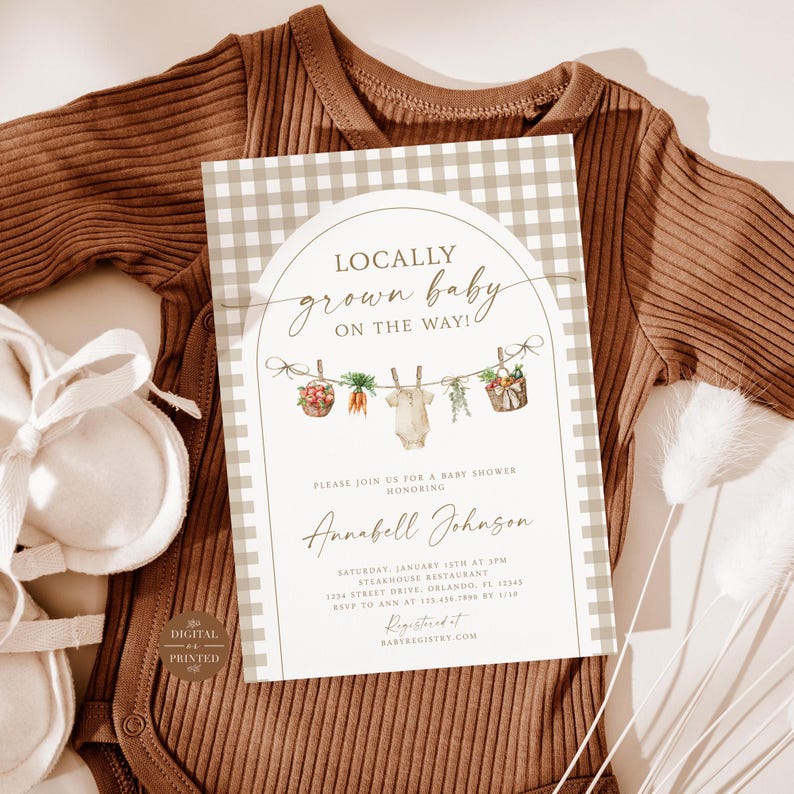 May include: A baby shower invitation with a gingham background and a watercolor illustration of a baby onesie hanging on a clothesline with vegetables. The text reads "Locally grown baby on the way!" and includes the name "Annabell Johnson".