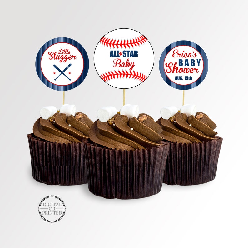 May include: Three chocolate cupcakes with baseball-themed toppers. The toppers feature baseballs and text that reads "Little Slugger", "All-Star Baby", and "Erica's Baby Shower Aug. 15th". Each cupcake is topped with a marshmallow.