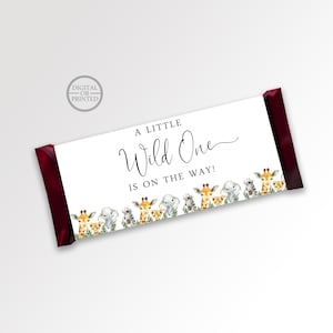 May include: A white chocolate bar wrapper with a red border. The wrapper has a black and white design with the text "A Little Wild One is on the way!" and a border of cartoon animals. The wrapper also has a small circle with the text "Digital or Printed".