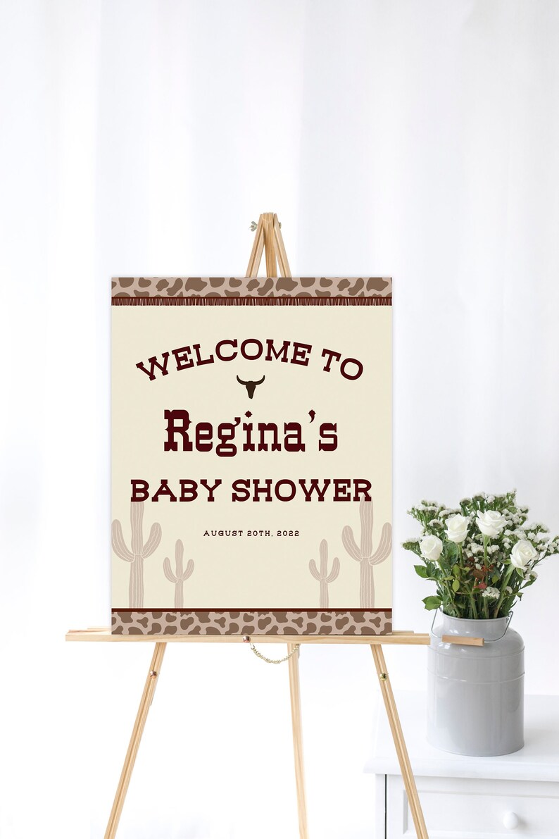 May include: Welcome to Regina's Baby Shower sign with a brown cowboy hat icon, cacti, and a leopard print border. The sign is on a wooden easel and the date is August 20th, 2022.