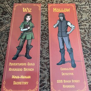 Op de afbeelding: Twee rechthoekige bladwijzers met een rode achtergrond en gouden decoratieve randen. De linker bladwijzer toont een personage met het label Wiz, Adventurers Guild Riversend Branch, Mage Healer, Secretary. De rechter bladwijzer toont een personage met het label Hollow, Consulting Detective, 221B Baker Street, Riversend.