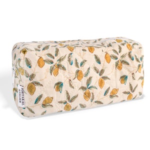 May include: A white quilted makeup bag with a lemon print. The bag has a zipper closure and a label that reads "PORTAKAL ATELIER".