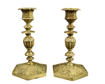 May include: A pair of antique brass candlesticks with ornate details and hexagonal bases.