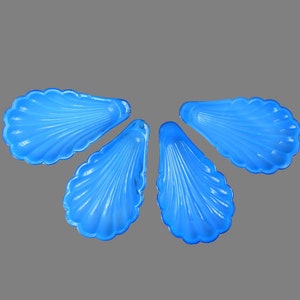 May include: Four blue plastic shell-shaped dishes. The dishes are arranged in a flower shape.