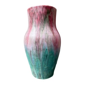 Könnte beinhalten: Eine dekorative Keramikvase mit einem einzigartigen Farbmuster. Die Oberseite der Vase ist tiefrosa, geht in eine Mischung aus Grün und Weiß über und endet in einem türkisfarbenen Sockel. Die Vase hat eine glatte, glänzende Oberfläche.
