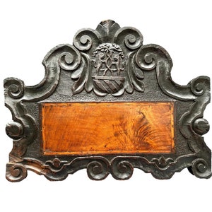 Könnte beinhalten: Ein dunkelholzgeschnitzter Rahmen mit einer rechteckigen Holztafel in der Mitte. Der Rahmen hat komplizierte Schnörkel und ein Wappen mit zwei Löwen oben.