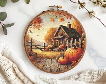 May include: A cross-stitch embroidery in a wooden hoop depicts a cozy autumn scene. A small house with a chimney is surrounded by fall foliage, pumpkins, and a wooden fence. The color palette includes shades of orange, brown, and green, evoking a sense of warmth and the harvest season.