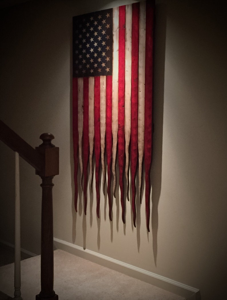 May include: A distressed American flag with red, white and blue stripes and stars. The flag is hanging on a wall and the stripes are dripping down like melted wax.