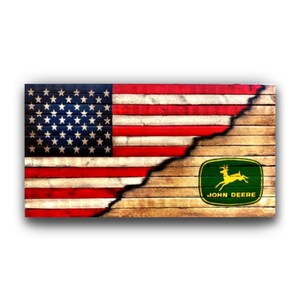 May include: A rectangular wooden sign with the American flag on the left and the John Deere logo on the right. The flag is red, white, and blue, and the logo is green and yellow. The sign has a distressed, rustic look, with a split down the middle.