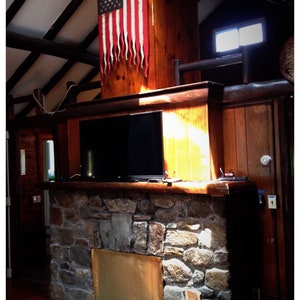 May include: A stone fireplace with a brass fire screen and a wooden log holder. An American flag hangs on the wall above the fireplace.