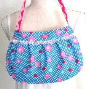 May include: A blue and pink polka dot fabric bag with a white lace trim and pink and red chevron straps.