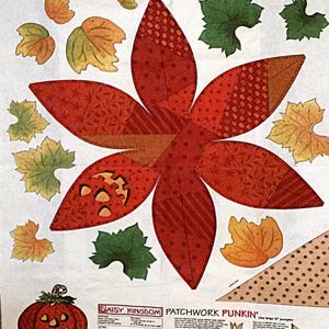 May include: A fabric panel featuring a patchwork pumpkin design with various leaves in shades of orange, green, and yellow. The central pumpkin is a large, multi-petaled shape with a jack-o'-lantern face. The text "DAISY KINGDOM PATCHWORK PUNKIN'" is visible.