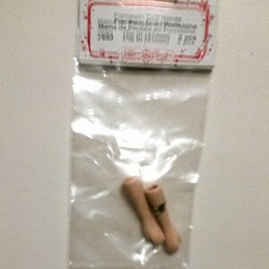 May include: Two porcelain doll hands in a clear plastic bag. The bag has a label that reads "Porcelain Doll Hands, Mains de Poup&eacute;e en Porcelaine, 5683, 1 1/8 in (31mm), 2 pcs".