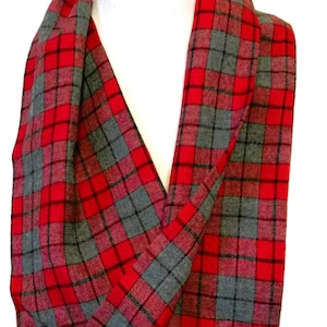 May include: A red, gray, and black plaid infinity scarf. The scarf is made of a soft fabric and is draped over a white mannequin head. The plaid pattern is a classic design, perfect for fall and winter.