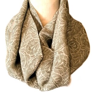 May include: A beige infinity scarf with a brown paisley pattern.
