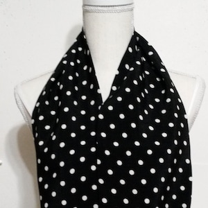 May include: A black and white polka dot scarf. The scarf is folded and draped around a white mannequin's neck.