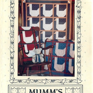 May include: A framed image of a quilt pattern called "The Goose Quilt" with a teddy bear sitting in a rocking chair. The quilt is made of blue, red, and white fabric. The image is surrounded by a border of geese and hearts. The text "Mumm's The Word" is printed below the image.
