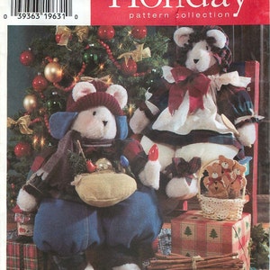 May include: A Simplicity Holiday pattern collection envelope, number 7439, featuring two plush bears dressed in winter clothing. One bear wears a red hat and blue pants, while the other wears a plaid dress and bonnet. A basket of small bear ornaments sits nearby.