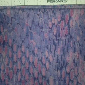 May include: Purple fabric with a pattern of pink and blue ovals. The fabric has a subtle texture.
