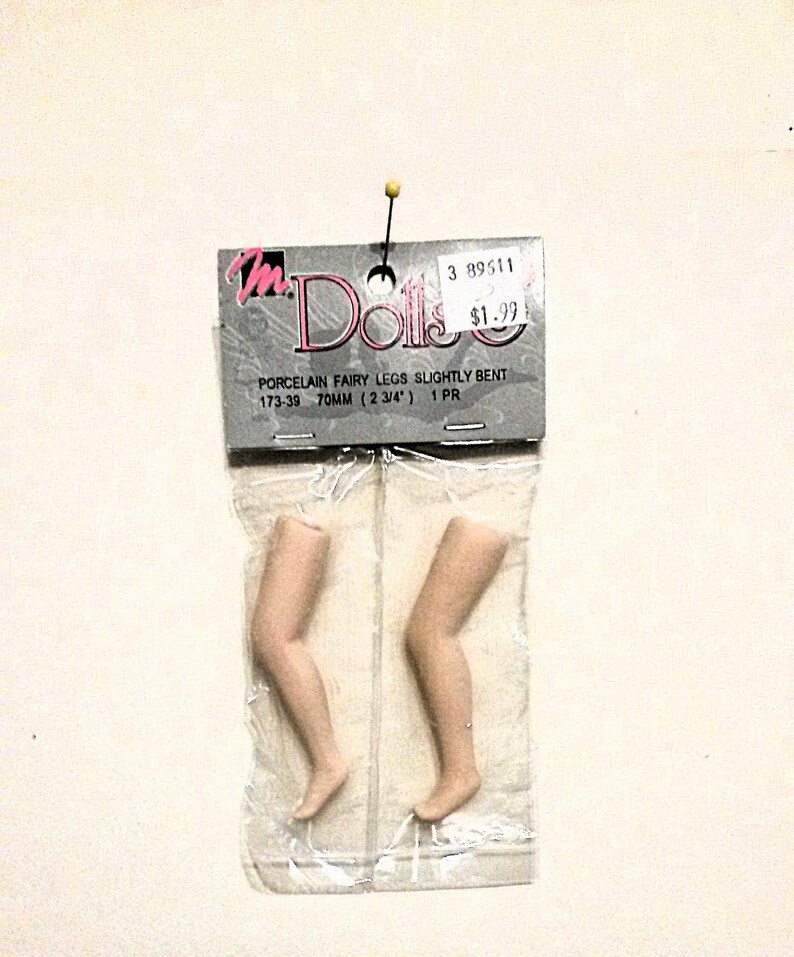 May include: A package of two porcelain fairy legs, slightly bent, in a clear plastic bag. The package is labeled "Porcelain Fairy Legs Slightly Bent 173-39 70mm (2 3/4") 1 PR".
