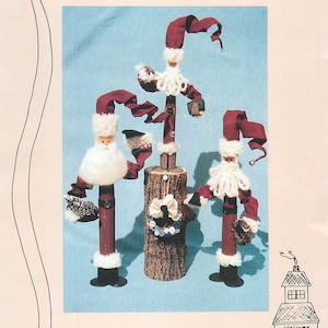 May include: A craft pattern for Hammer Handle Santa dolls. The image shows three Santa figures with red fabric hats and arms, white beards, and black boots. The text reads "Down Emory Lane" and "Hammer Handle Santa 12", 14" or 16".
