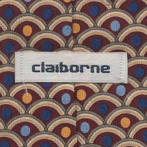 May include: A red, brown, and beige patterned silk tie with a white label that reads "Claiborne". The pattern features blue and orange circles.