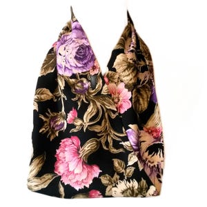 May include: A black tote bag with a floral pattern. The bag features large pink and purple flowers with brown and green leaves. The bag has a V-shaped opening and a white background.