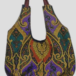 May include: A purple, green, gold, and orange paisley patterned tote bag with brown straps.