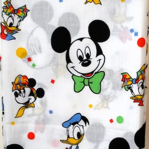 May include: White fabric with a repeating pattern of various Disney characters, including Mickey Mouse, Minnie Mouse, Donald Duck, and Goofy. The characters are depicted in a cartoon style with bright colors and simple designs.