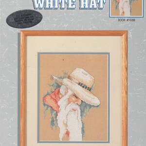 May include: A counted cross stitch pattern book featuring a man with a white hat and a long white beard. The title of the pattern is "He Wore A White Hat". The book is by Lana Gordon-Rast and is part of the Color Charts series. The book is 8 inches by 10 inches and fits into a standard 8 inch by 10 inch frame.
