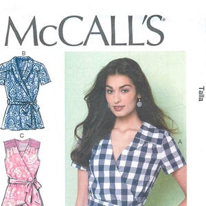 May include: McCall's M7358 sewing pattern envelope featuring a navy and white gingham wrap top with short sleeves, a V-neckline, and a tie waist. The envelope displays three variations of the top, including blue and pink floral patterns.