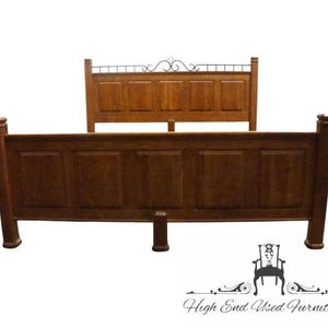 May include: A wooden bed frame with a headboard and footboard. The headboard features a decorative metal accent. The bed frame is made of dark brown wood and has a classic design. The bed frame is a full or queen size.