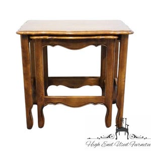 May include: A medium brown wooden nesting table featuring a rectangular top with curved edges and four legs connected by arched aprons. The table has a smooth finish and a sturdy construction, showcasing a classic design with visible wood grain.