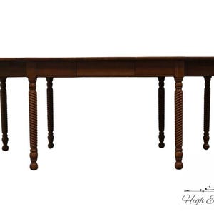 May include: A dark brown wooden dining table with a rectangular top and turned legs. The table has a leaf extension and measures approximately 96 inches long when fully extended. The legs have a rope-like design.