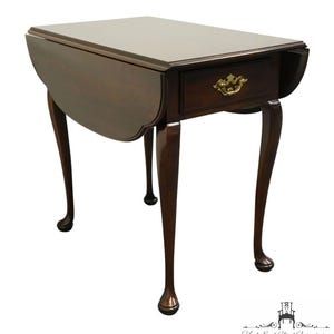 May include: A dark brown, drop-leaf side table with a single drawer and brass hardware. The table has four curved legs and measures approximately 30 inches long when open. The table is made of wood and has a glossy finish.