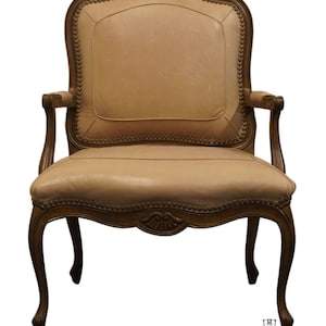 Puede incluir: Un sill&oacute;n de cuero beige con un marco de madera tallada y patas ornamentadas. El sill&oacute;n tiene un respaldo alto y brazos, y el asiento est&aacute; tapizado en cuero suave y flexible.