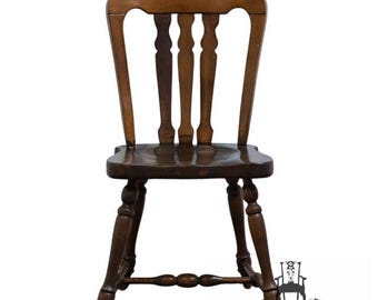 May include: A dark brown wooden chair with a curved back and four vertical spindles. The chair has a rounded seat and turned legs, with a decorative stretcher between the legs. The chair is likely antique or vintage.