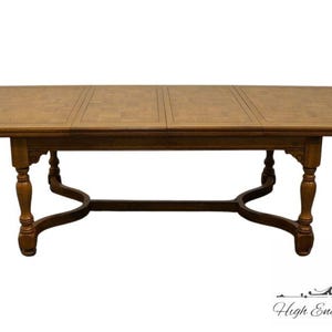 May include: A rectangular wooden dining table with a light brown surface and dark brown trim. The table has four ornate legs and a decorative base. The table is a classic piece of furniture.