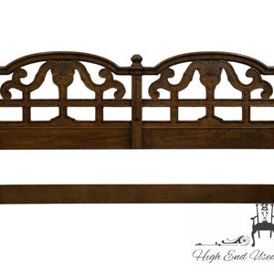 May include: A dark brown wooden headboard with an arched top and decorative carved details. The headboard features a rectangular grid pattern and ornate scrollwork. The design is symmetrical, with a central vertical support and two arched sections.