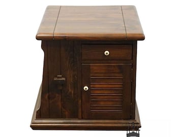 Puede incluir: Una mesa auxiliar de madera marrón oscuro con un cajón y una puerta de armario con lamas horizontales. La mesa tiene una tapa rectangular y una base decorativa. La ferretería es de color claro.