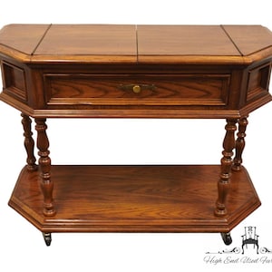 May include: A wooden octagonal serving cart with a single drawer and a lower shelf. The cart has turned legs and casters. The cart is made of a dark wood with a rich grain.