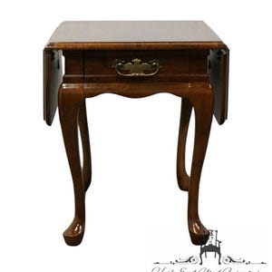 May include: A dark wood end table with a single drawer and a brass pull. The table has a drop leaf on each side and cabriole legs.